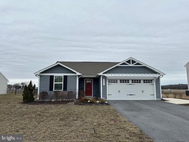 ranch-style home with aphalt driveway, board and batten siding, an attached garage, and a front yard