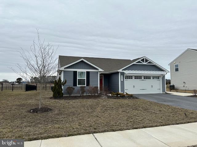 view of front facade with driveway, a garage, fence, and a front lawn