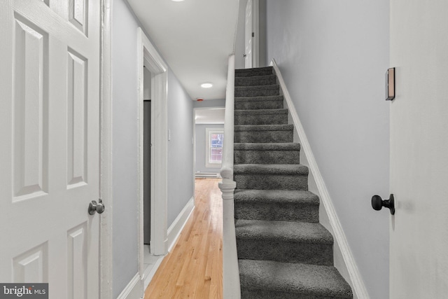 staircase featuring baseboards and wood finished floors