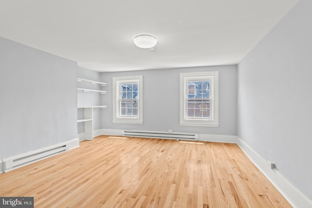 spare room with a baseboard heating unit, plenty of natural light, and light wood-style flooring