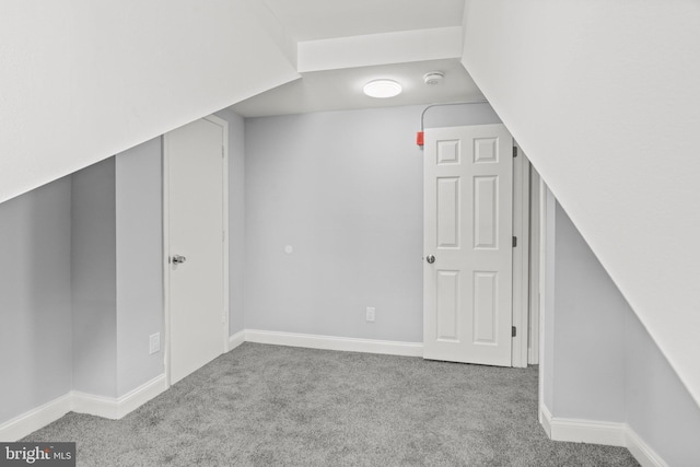 bonus room with baseboards and light colored carpet