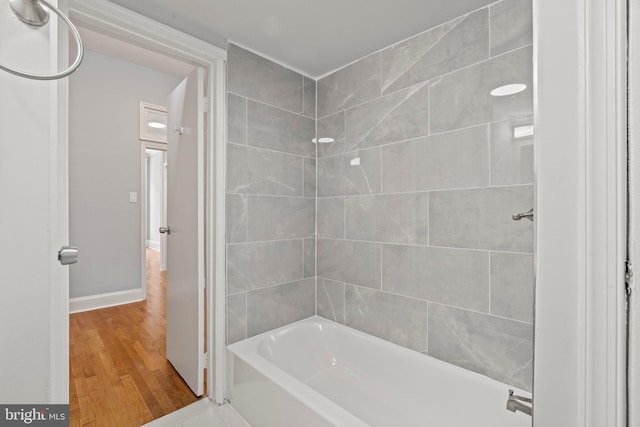 bathroom featuring shower / bath combination, baseboards, and wood finished floors