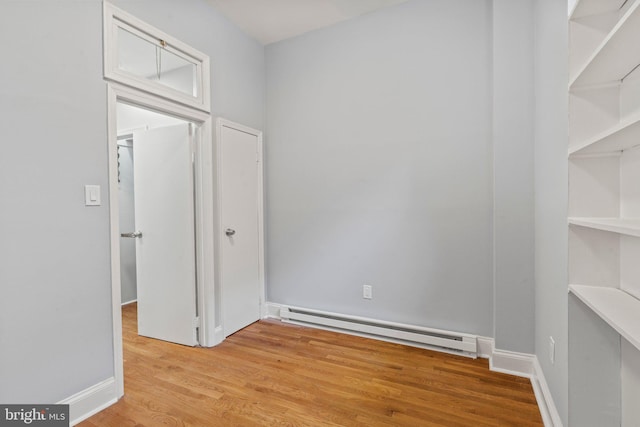 unfurnished room featuring light wood-style flooring, a baseboard heating unit, and baseboards