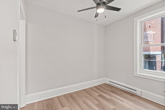 spare room with plenty of natural light, a baseboard heating unit, and light wood-style flooring