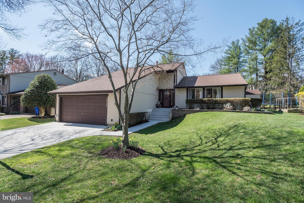 view of front of house with a front lawn, a trampoline, concrete driveway, and an attached garage