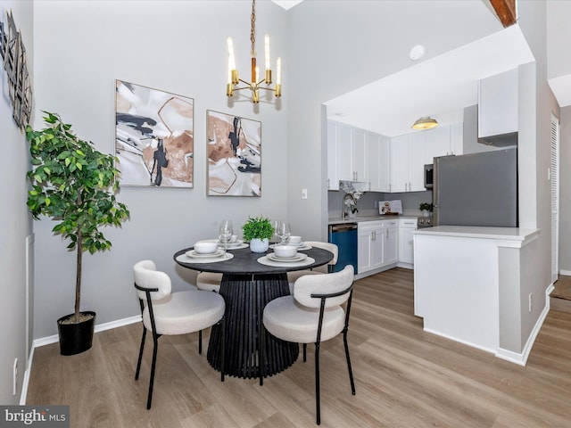 dining area featuring baseboards, a notable chandelier, and light wood finished floors