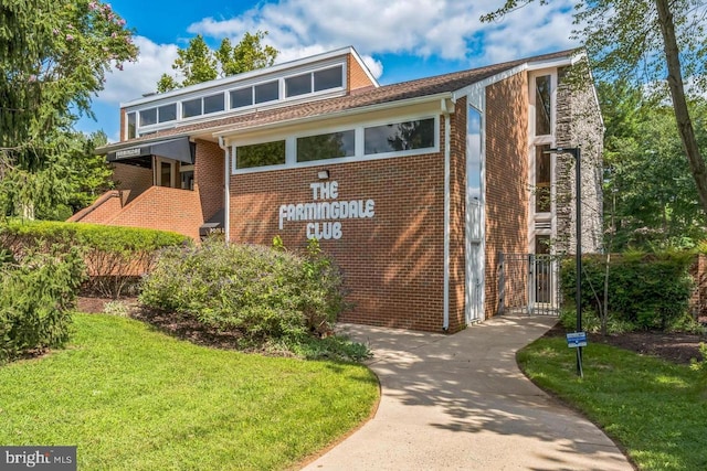 exterior space featuring concrete driveway, brick siding, and a front lawn