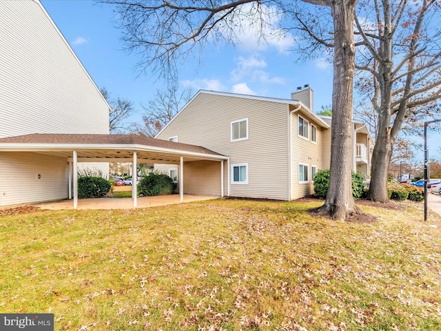 exterior space featuring a chimney, a lawn, and a carport