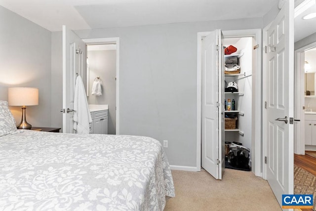 bedroom with light carpet, baseboards, a closet, and ensuite bathroom