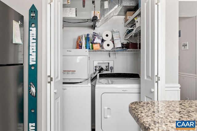 laundry room with laundry area, a wainscoted wall, and separate washer and dryer