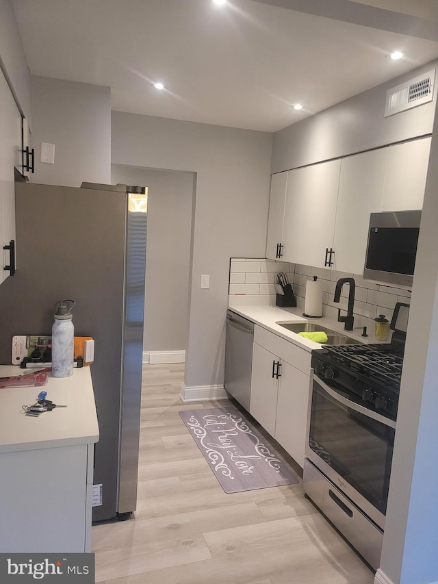 kitchen featuring appliances with stainless steel finishes, tasteful backsplash, light countertops, and white cabinetry