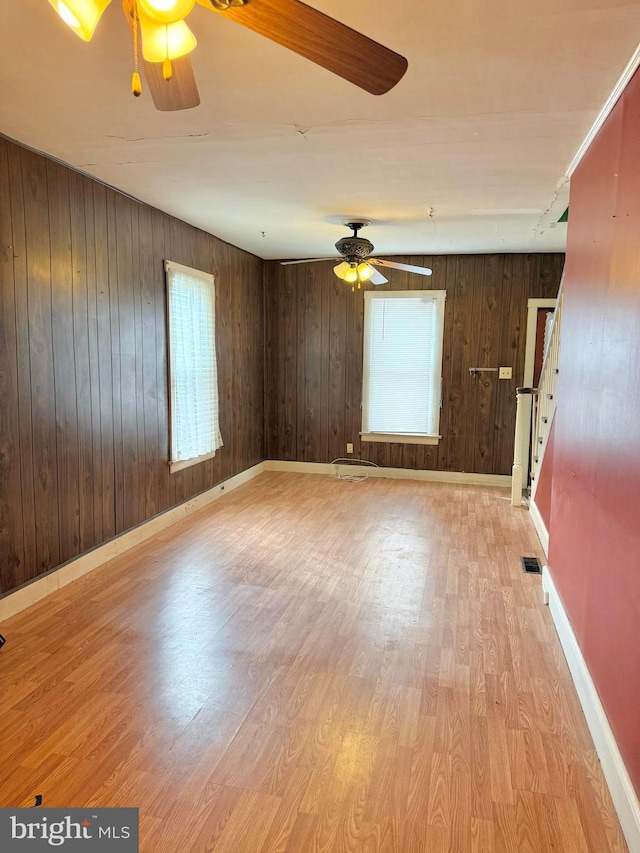 empty room with ceiling fan, light wood finished floors, visible vents, and baseboards