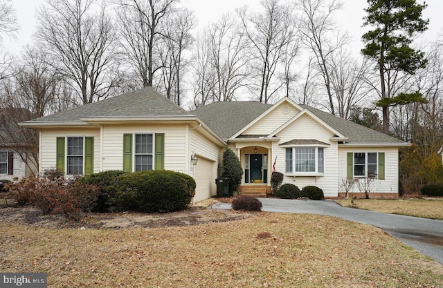 view of front facade with an attached garage, driveway, a front lawn, and a shingled roof