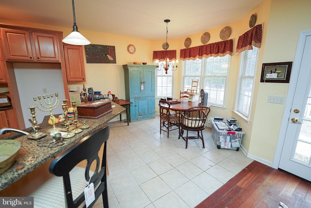 kitchen featuring light stone counters, a chandelier, decorative light fixtures, and brown cabinetry