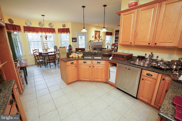 kitchen featuring stainless steel dishwasher, dark stone countertops, pendant lighting, and a sink