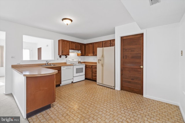 kitchen with under cabinet range hood, a peninsula, white appliances, light countertops, and brown cabinetry