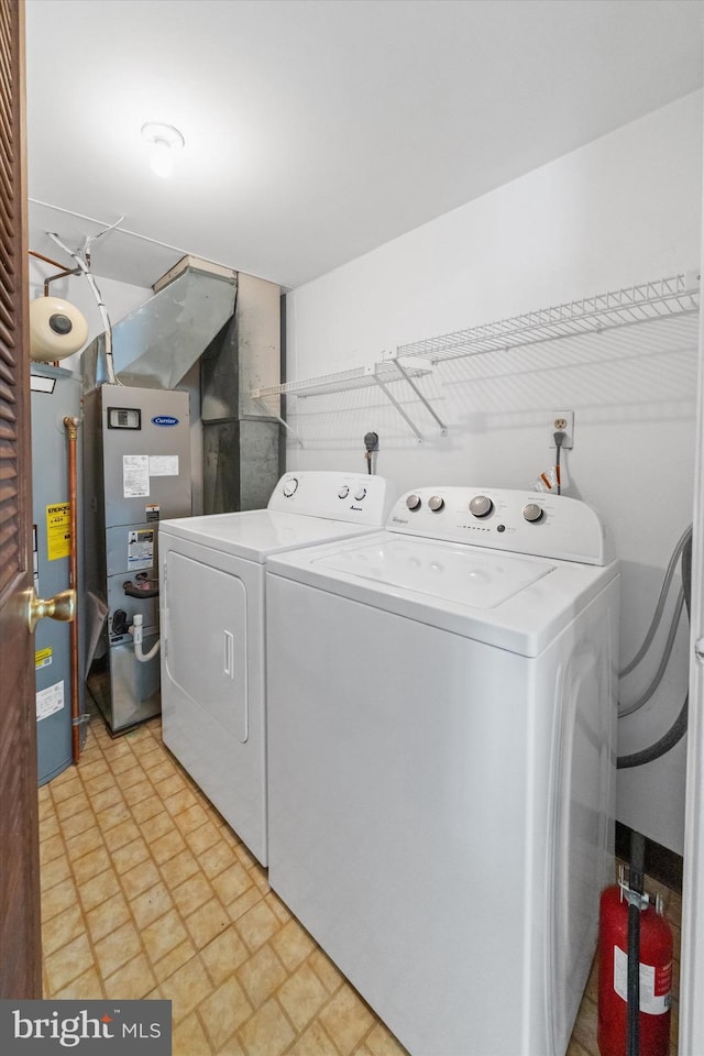 laundry room featuring heating unit, laundry area, water heater, and washer and dryer