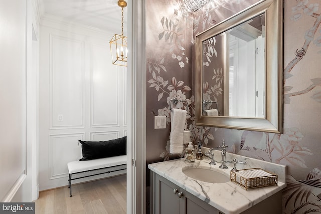 bathroom featuring wood finished floors, vanity, and wallpapered walls