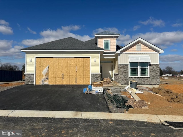 view of front of property with driveway, stone siding, and a garage