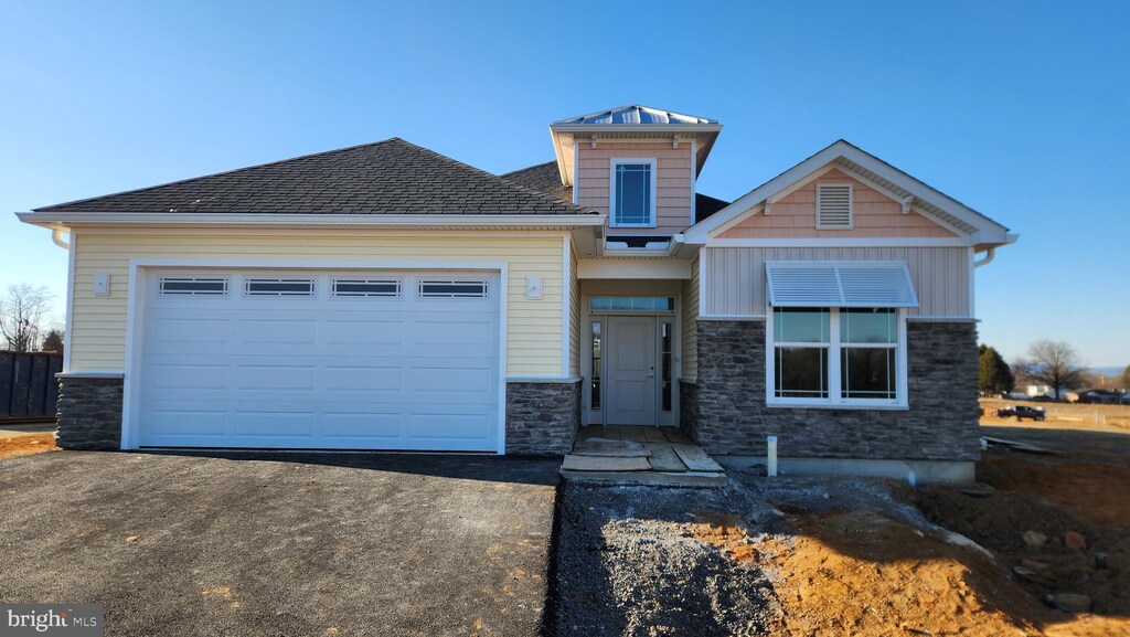 craftsman house with a garage, stone siding, aphalt driveway, and board and batten siding