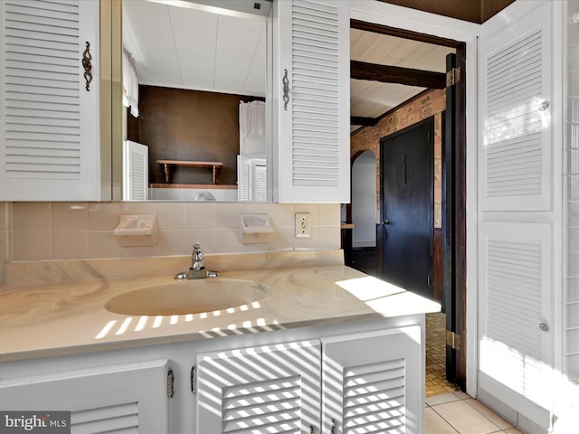 kitchen featuring light tile patterned floors, decorative backsplash, light countertops, and a sink