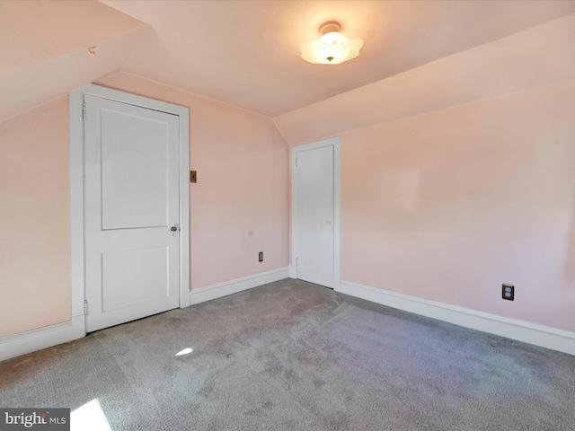 additional living space with vaulted ceiling, baseboards, and light colored carpet