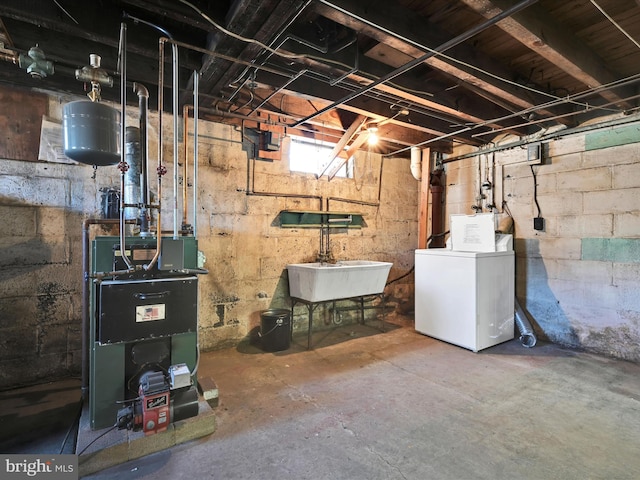 below grade area with washer / clothes dryer, a heating unit, and a sink