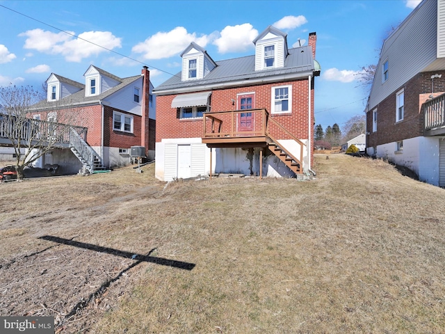 back of house with stairs, metal roof, a lawn, and brick siding