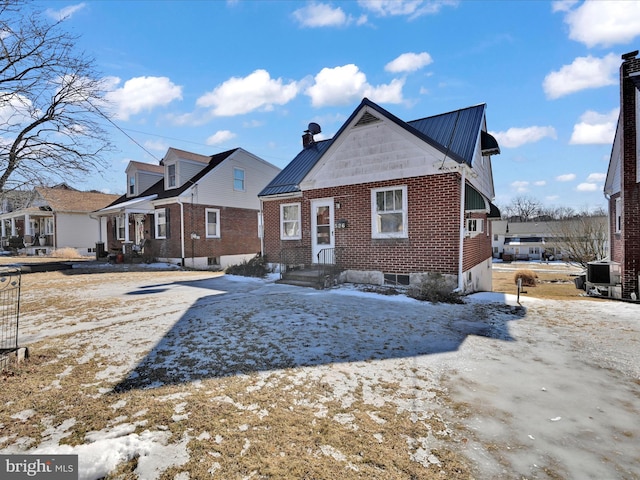 view of front of house with a standing seam roof, brick siding, metal roof, and a chimney