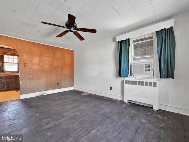 spare room featuring radiator heating unit, arched walkways, and baseboards