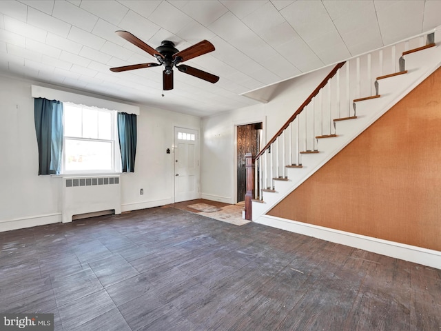 entrance foyer featuring wood finished floors, a ceiling fan, baseboards, stairway, and radiator