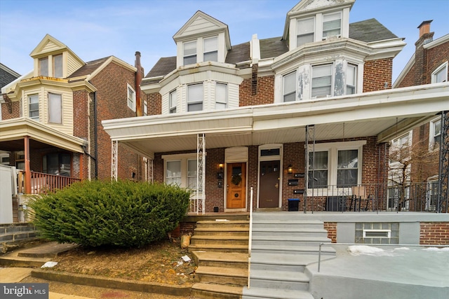 view of front facade featuring brick siding and a porch