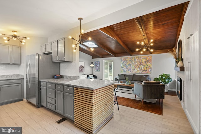 kitchen featuring open floor plan, stainless steel refrigerator with ice dispenser, gray cabinetry, and an inviting chandelier