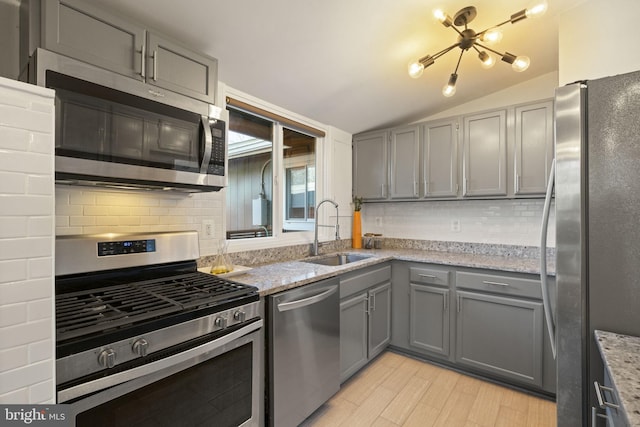 kitchen featuring a sink, stainless steel appliances, light stone counters, and gray cabinets