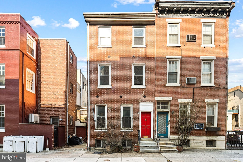 multi unit property featuring entry steps, an AC wall unit, brick siding, and cooling unit