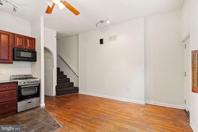 kitchen featuring black microwave, dark wood-type flooring, visible vents, stainless steel gas range, and dark countertops