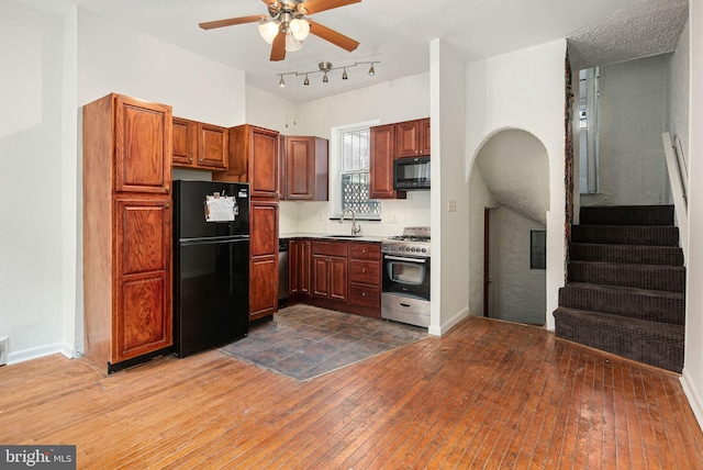 kitchen featuring baseboards, a ceiling fan, dark wood-style floors, black appliances, and a sink