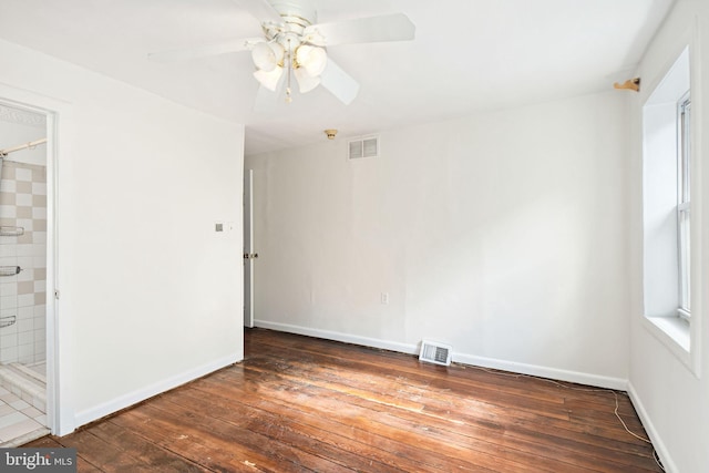 spare room featuring dark wood-type flooring, a ceiling fan, visible vents, and baseboards