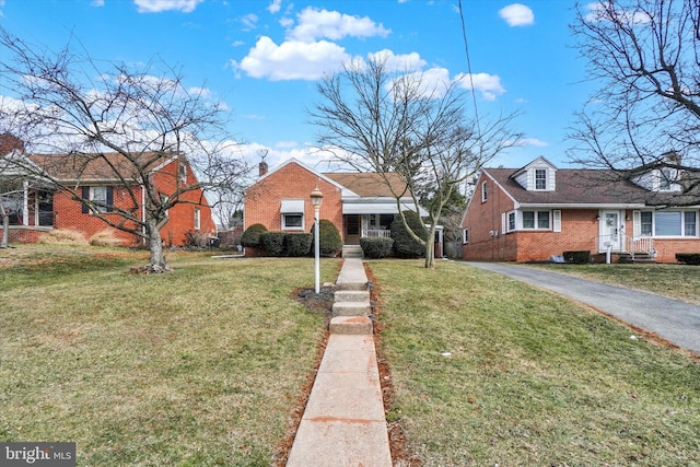 bungalow featuring driveway, a front lawn, and brick siding