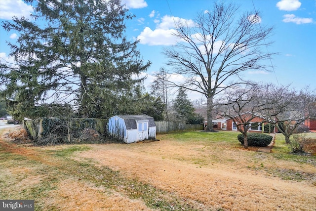 view of yard with an outbuilding, fence, and a shed