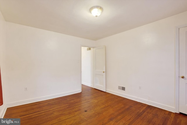 spare room featuring baseboards, visible vents, and dark wood-type flooring