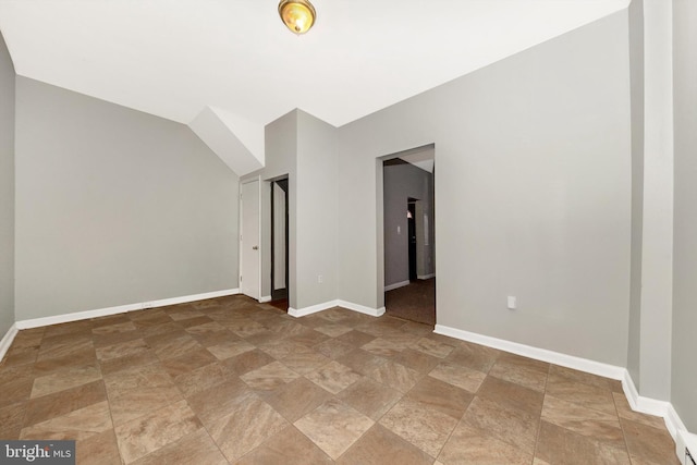 spare room featuring lofted ceiling and baseboards