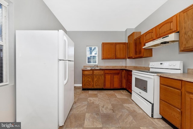 kitchen with white appliances, brown cabinetry, light countertops, under cabinet range hood, and a sink