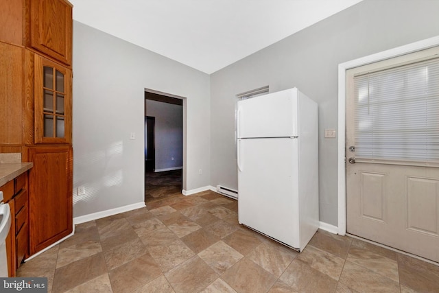 kitchen featuring brown cabinetry, baseboards, baseboard heating, and freestanding refrigerator