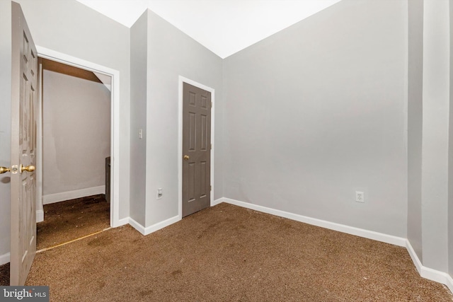 unfurnished bedroom featuring carpet floors, lofted ceiling, and baseboards