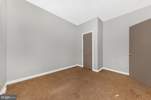 unfurnished room with lofted ceiling, carpet flooring, and baseboards