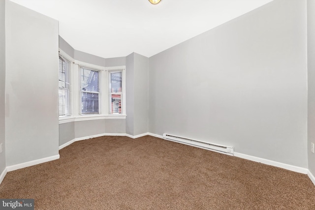 spare room with a baseboard heating unit, carpet flooring, and baseboards