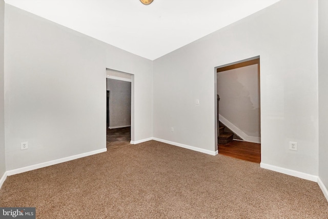 spare room featuring carpet flooring, baseboards, and stairs