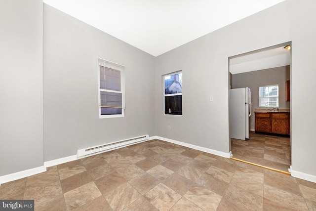 empty room with baseboard heating, a sink, and baseboards