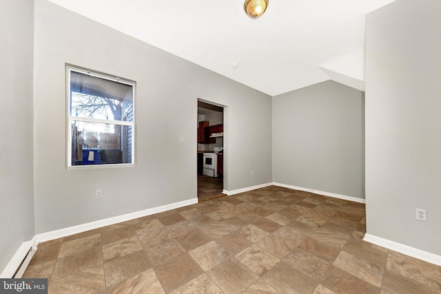 empty room with lofted ceiling, stone finish flooring, a baseboard radiator, and baseboards